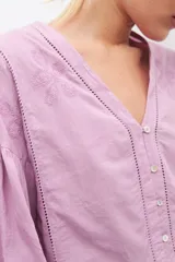 Blusa blanca de manga larga con escote en V y bordados en el frente.