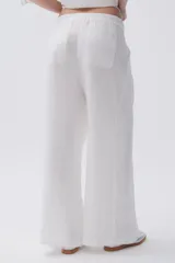 Pantalón de lino blanco, de pierna ancha, con pinzas en el frente, botón en la cintura y bolsillos laterales y traseros.