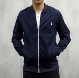 Campera bomber azul marino de gabardina con cierre frontal y logo bordado en el pecho.