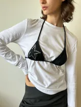 Bikini de dos piezas color blanco, con corpiño triangular decorado con tachas hotfix en forma de estrella y bombacha a juego con textura brillante.