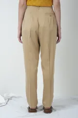 Pantalón de vestir color beige, de corte recto, con pinzas en la parte delantera y cierre con botón.