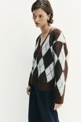 Jersey de punto con diseño de rombos en tonos marrón y gris, escote en pico con detalle de encaje, manga larga y cierre frontal con botones.