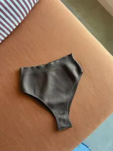 Conjunto de bikini negro de hilo, con corpiño bandeau y bombacha vedetina de tiro alto.