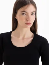 Top de punto morley color negro, con silueta ajustada al cuerpo, mangas cortas y escote redondo pronunciado.