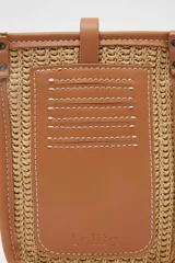 Porta celular color tostado con detalles de rafia y correa larga para colgar.