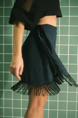 Minifalda azul con brillos, corte pareo y flecos negros en el ruedo.