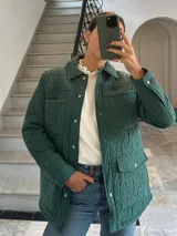 Campera verde militar acolchada con cuello camisero, cierre frontal con botones a presión, bolsillos de parche con solapa en el pecho y bolsillos laterales.