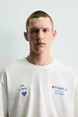 Camiseta de corte relajado con cuello redondo y manga corta. Presenta un diseño con estampados en tono azul con efecto lavado en la parte frontal.