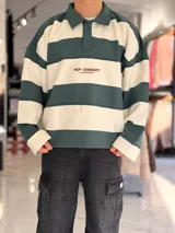 Buzo polo de rayas horizontales en gris oscuro y blanco, con cuello camisero, cierre frontal parcial y corte oversize. Presenta un gran número 88 estampado en la espalda en color bordó junto con la inscripción VCP/ARG.