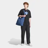 Remera Adidas de algodón color negro, con ajuste holgado, cuello redondo y moldería clásica de manga corta. Presenta un estampado gráfico frontal inspirado en el logo Trefoil con un diseño de personaje estilizado en tonos azules y blancos.