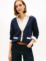 Cárdigan de punto azul marino con cuello en V, cierre frontal con botones dorados y bolsillos delanteros con ribetes en contraste. Presenta detalles en lurex en el cuello y los bolsillos, y logo de la marca bordado en el pecho.