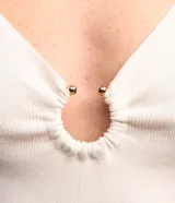 Blusa de manga corta confeccionada en tejido de viscosa texturizado, con escote en V profundo que presenta un detalle de aro metálico central.