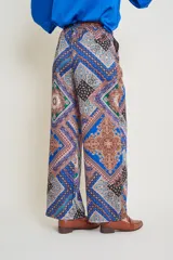 Pantalón italiano de seda con estampado geométrico en tonos verde, rosa, amarillo y negro. Tiene cintura elastizada y bolsillos laterales.