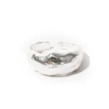 Anillo plateado con textura irregular y abertura ajustable.