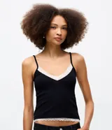 Musculosa de rib color negro, con breteles finos y escote en V con detalle de encaje blanco en el borde superior y en el ruedo.