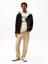 Cortavientos negro de corte amplio, confeccionado en tejido técnico ligero que repele el agua y totalmente forrado. Cuenta con capucha fija, cuello alto, cierre de cremallera, dos bolsillos delanteros con cremallera, parche de Tommy en el pecho y forro con diseño integral de la insignia de Tommy.