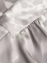 Blusa de satén gris con estampado abstracto en blanco, escote en V y mangas cortas.