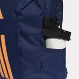 Mochila Adidas PrimeLift de color azul marino con detalles en naranja. Cuenta con compartimento principal con cierre, compartimento externo para notebook, bolsillos frontales y laterales, y correas de compresión laterales. El panel trasero es de malla para mayor ventilación.