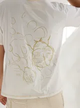 Remera color crudo con estampado en la espalda de una ilustración de una planta con flores.