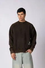 Buzo de cuello redondo con efecto desgastado y lavado vintage en color marrón oscuro. Presenta un calce amplio y cómodo, con puños y ruedo acanalados, y un pequeño logo estampado en la parte inferior frontal.