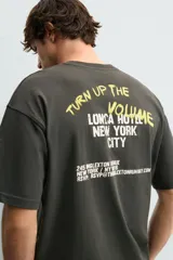 Camiseta de algodón con corte relajado, cuello redondo y manga corta. Presenta estampados gráficos a contraste en el frente con inscripciones tipo señalética.