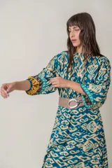 Vestido largo de viscosa con estampado abstracto en tonos azul petróleo y beige. Tiene mangas largas anchas terminadas en puño fruncido, corte en la cintura y bajo con volado y guarda.