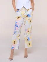 Pantalón ankle de sastrería color blanco con estampado floral multicolor, de corte recto y tiro medio con cordón de ajuste en la cintura.