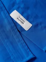 Vestido camisero de corte oversize confeccionado en algodón orgánico. Presenta cuello inglés, cierre frontal de botones, mangas largas con puños abotonados y largo hasta la rodilla. Incluye el logo de la marca bordado en uno de los puños.