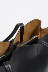 Bolso shopper de piel color borgoña, con textura granulada, asas de hombro y cierre de cordón. Presenta el logo metálico de Bimba y Lola en el frente.