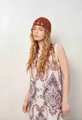 Vestido midi sin mangas, con escote en V y estampado estilo paisley en tonos marrones y violetas sobre fondo blanco.