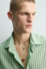 Camisa de corte relajado confeccionada en tejido fluido con mezcla de lyocell. Presenta diseño de rayas verticales, cuello solapa, manga larga con puños abotonados, bolsillos de plastrón con solapa en el pecho y cierre frontal con botones a presión.