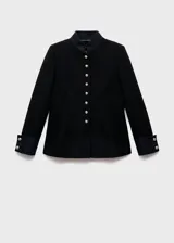 Chaqueta negra de estilo militar entallada, con cuello mao, cierre frontal de botones dorados con efecto joya y manga larga con trabillas y puños abotonados.