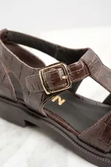 Sandalias cangrejeras de cuero marrón con textura croco, hebilla dorada y suela plana.