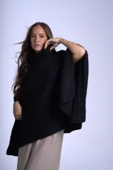 Poncho tejido color beige, con cuello alto y corte asimétrico.