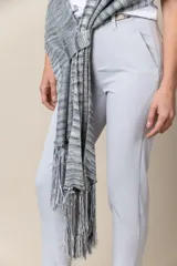 Chal de hilo artesanal color verde con detalles en gris y blanco, con flecos en los extremos y presilla para sujetarlo.