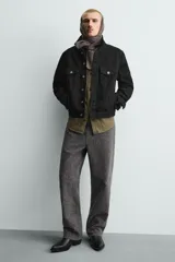 Bota de media caña en color negro, con diseño de arnés que incluye tiras, argollas metálicas y tachas decorativas alrededor del tobillo. Presenta punta fina y tacón cuadrado.