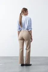 Pantalón de mujer color beige, de corte recto y tiro alto, con costuras frontales marcadas que recorren la pierna.