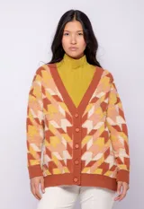 Cardigan de tejido de punto color ladrillo con diseño geométrico con relieve en tonos amarillo, naranja y blanco. Tiene escote en v y cierre con cinco botones de plástico.