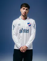 Camiseta de fútbol Umbro del Club Nacional de Football, modelo Home 2026 de manga larga. Diseño en color blanco con detalles en azul y rojo en el cuello y puños. Incluye logo de Umbro, escudo del club y sponsor Antel en el frente.