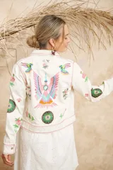 Campera de algodón color blanco con estampado de flores, plumas y colibríes, cuello camisero y cierre frontal con botones.