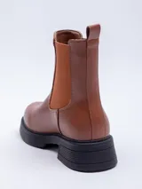 Bota Chelsea de cuero sintético color negro, con elástico lateral y suela track.