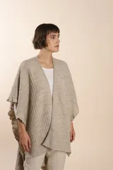 Ruana tejida en punto fantasía color beige, con efecto de volado en los bordes. Es una prenda liviana, suave y etérea.