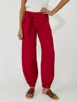 Pantalón de lino color rojo, de corte holgado con botamangas elastizadas y diseño cruzado en la cintura con lazo ajustable.