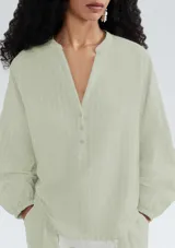 Blusa verde a rayas verticales con cuello en V y cierre frontal con botones. Mangas 3/4 y corte holgado.