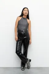 Pantalón negro de cuero sintético, tiro alto, corte oxford y costuras verticales a lo largo de las piernas.