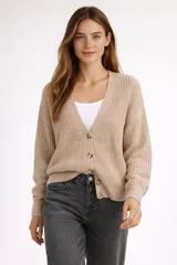 Cardigan de punto acrílico color beige, con cuello en V, cierre frontal de botones y diseño holgado.