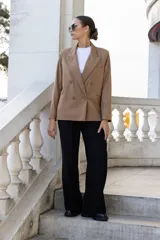 Blazer color camel de corte clásico, con solapas de muesca, doble botonadura y bolsillos delanteros con solapa.