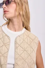 Chaleco color crudo con diseño acolchado de rombos y cuello redondo.