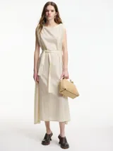 Vestido midi de algodón color crudo, con diseño tipo túnica, cuello redondo y lazo ajustable en la cintura para entallar la silueta. Presenta detalles de bordado sutil en el cuello y las sisas.