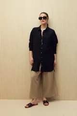 Vestido camisero negro de silueta amplia, con cuello camisero, botonadura frontal completa y mangas largas.